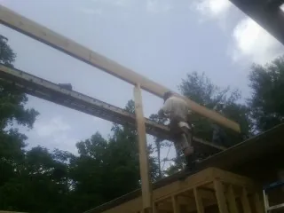 Carpenter setting a ridge beam over a new addition frame — Ice Dam Removal by Roofing Brothers in Keyes