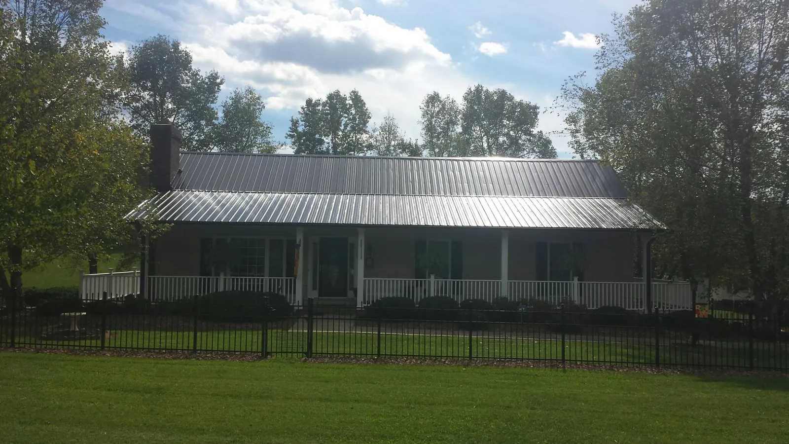 Gray metal roof on a brick ranch with a full width front porch — Gutter Guard Installation work by our crew in Keyes