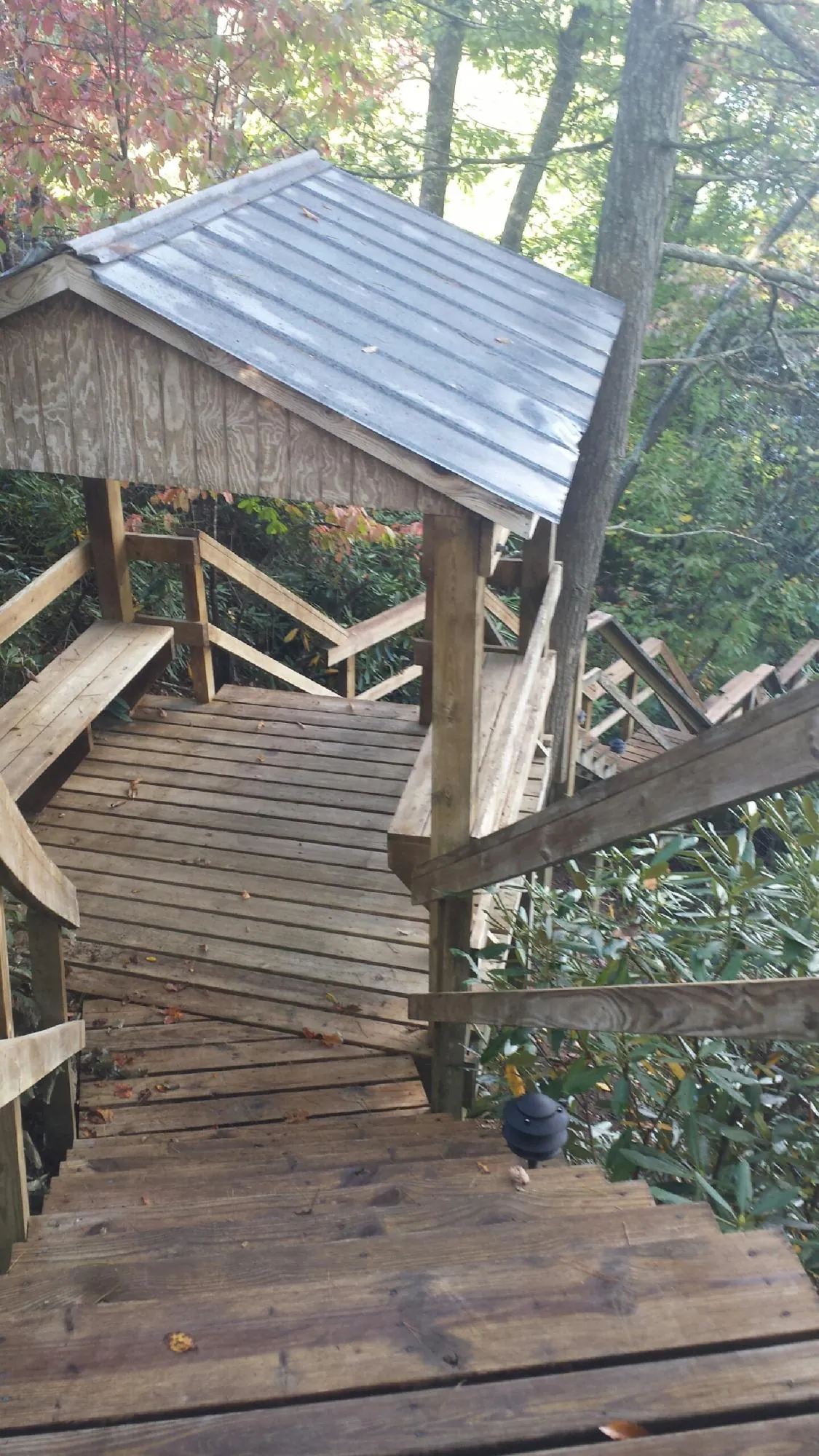 Metal roofed shelter over wooden steps on a wooded walkway — Skylight Repair & Installation work by our crew in Keyes